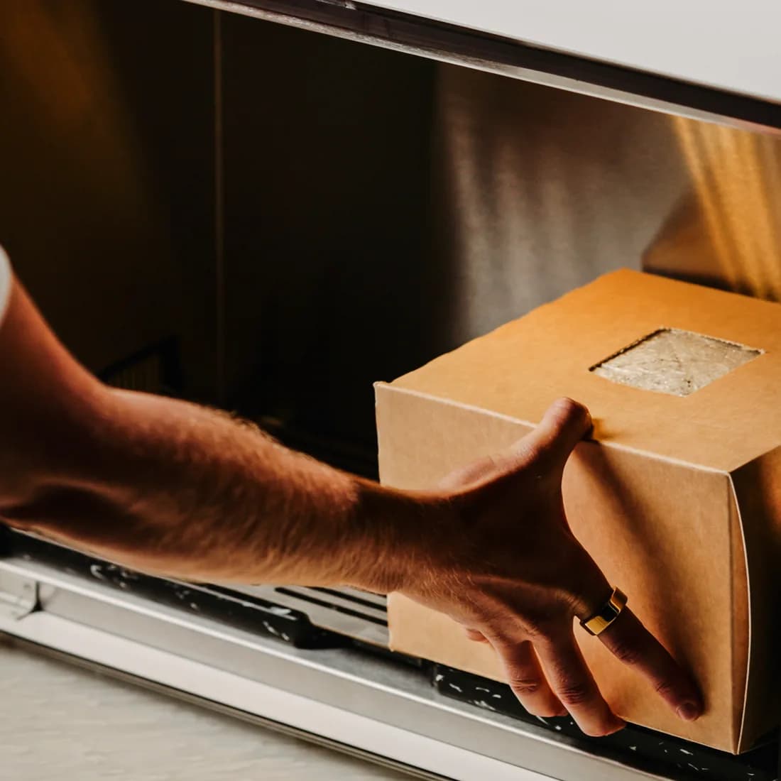 A hand sliding a kraft-boxed fruiting block into the Flush cabinet